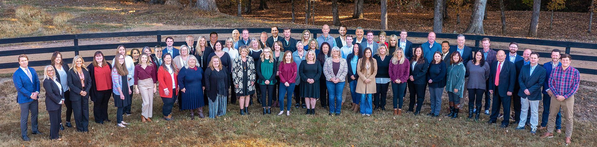 Meet Our Team - Arial View of RSS Insurance Team Standing in an Open Outdoor Area in Front of a Fence Looking at Camera in the Sky Wide